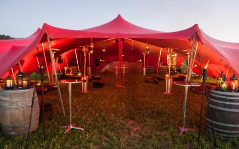 a red stretch tent stagged on a open field with lighting 